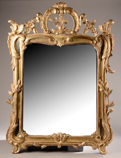 null 
Miroir en bois sculpté et redoré à décor de volutes feuillagé, fleurs et agrafes...