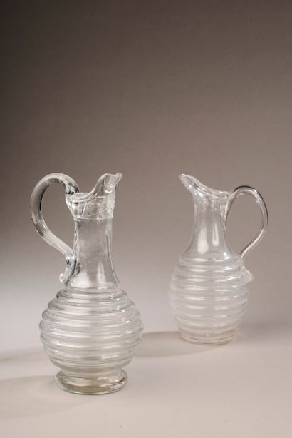 null Two blown glass pitchers, the handle applied by heat, the body ringed.

Normandy,...