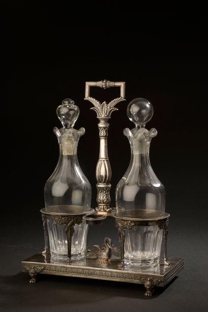 null A silver oil and vinegar cruet with two cups decorated with horns of plenty,...