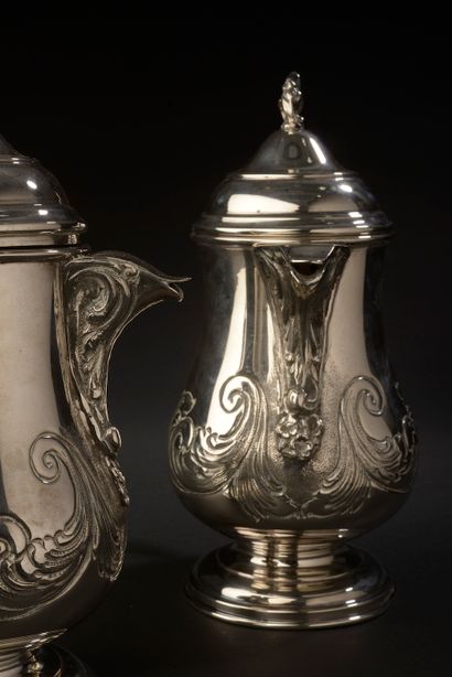 null Pair of silver coffee pots on pedestal with embossed decoration of foliage.

England,...