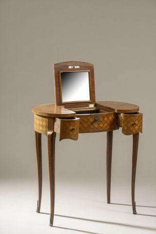 null A mahogany dressing table of kidney shape decorated with a marquetry of mahogany...