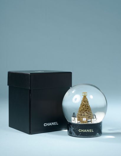 CHANEL.

Glass snow globe on a black lacquered...
