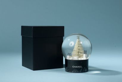 CHANEL.

Glass snow globe on a black lacquered...