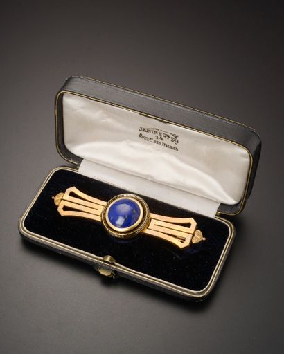 null 18k yellow gold brooch with a lapis lazuli cabochon in a black enamel setting.

Accompanied...