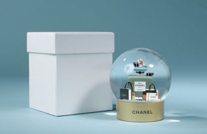 CHANEL.

Glass snow globe on a gold lacquered...