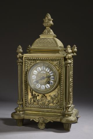 Bronze clock surmounted by a dome topped...