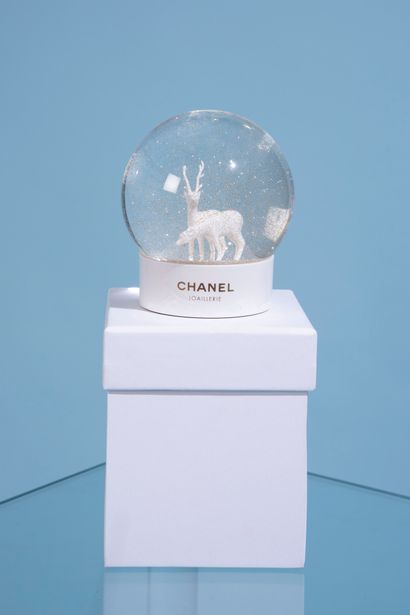 CHANEL. 

Glass snow globe on a white lacquered...