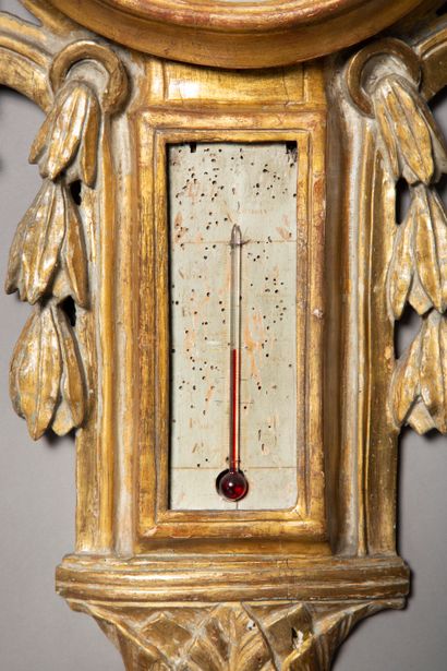 null Baromètre-thermomètre en bois sculpté et doré, il présente un trophée noué sur...