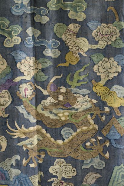 null CHINE - XIXe siècle.
Robe jifu en kesi bleu à décor de dragons pourchassant...