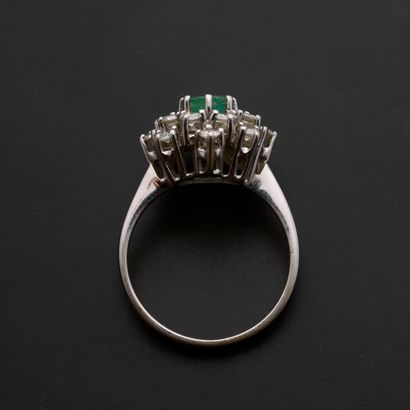 null 18k white gold flower ring set with an oval emerald in a setting of sixteen...