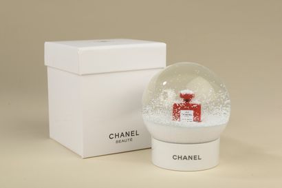 CHANEL. 
Glass snow globe on a white lacquered...