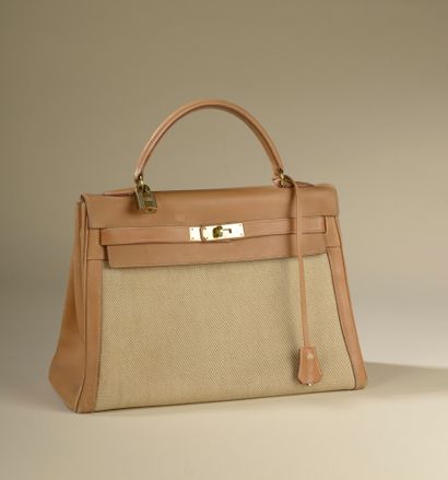null HERMÈS. 
Kelly" bag 32 cm in smooth gold leather and canvas H, the jewelry in...