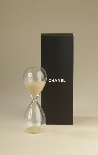 null CHANEL.
Sablier en verre et sable crème. 
Haut. : 14,5 cm
Accompagné de sa boîte....