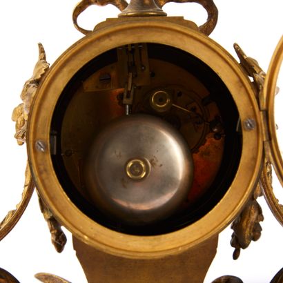 null Gilded bronze and brass clock, topped by a cassolette, resting on a barrel with...