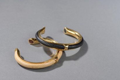 null HERMES.

Deux bracelets rigides ouverts en métal doré gainé de cuir noir et...