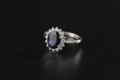 null Bague en or gris 18k, ornée d'un saphir ovale dans un entourage de seize diamants...