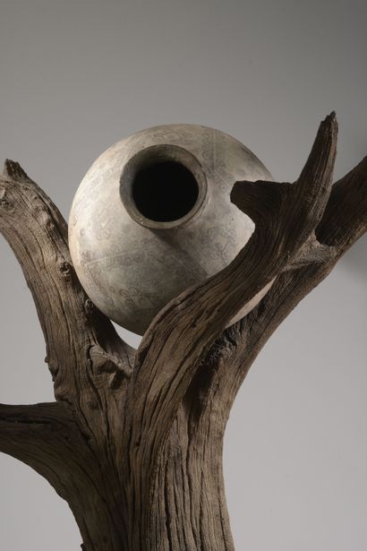 null Sculpture remployant un arbre en bois flotté soutenant une jarre en céramique...