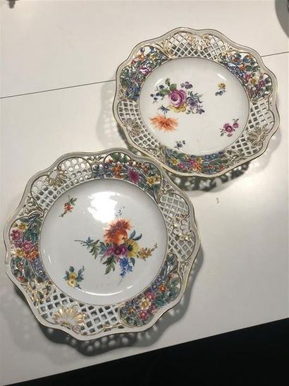 null Deux assiettes en porcelaine à décor polychrome de fleurs, l'aile à décor ajouré...