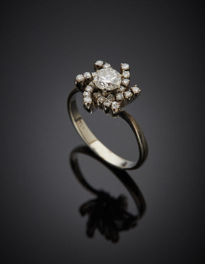  BAGUE « fleur » en or gris (750) serti d'un diamant taille brillant entouré de petits...