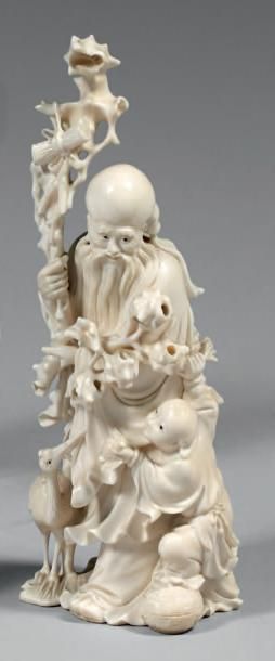 CHINE - XXe siècle Groupe en ivoire, Shoulao debout avec un enfant et une grue, s'appuyant...