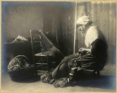 null Photographe non identifié. Jeune bretonne ravaudant un filet, dans un intérieur,...