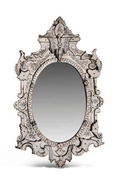 Important miroir biseauté de forme ovale, inscrit dans un encadrement ovale, l’e...