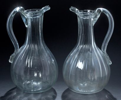 null 两只玻璃苹果酒壶，带棱纹和镶边的形状，凸起的壶嘴，有把手。
诺曼底，18世纪末
高度：28.5厘米。
