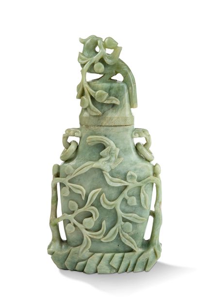 null 中国，20世纪

青瓷蛇纹石覆盖的花瓶，有轻微的白色脉络，在其边缘高浮雕和圆雕两棵桃树的叶子和水果。盖子上有一只鸟，嘴里叼着一根桃树枝。两个手柄可容纳...