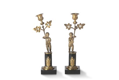 null PAIRE DE FLAMBEAUX en bronze ciselé figurant deux chérubins brandissant un bouquet...