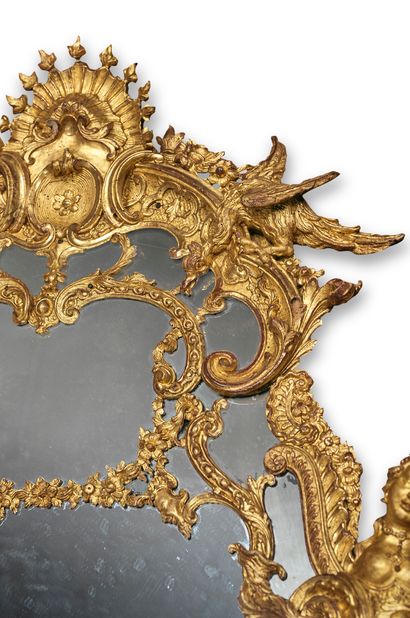 null 
A MONUMENTAL MIRROR with carved and gilded wood glazing, richly decorated with...
