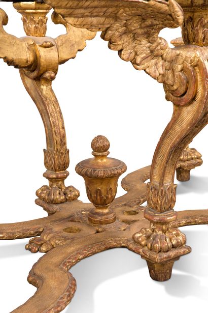 null A carved and gilded wood table, it rests on four uprights in sheath with lions'...