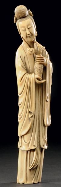 CHINE Sujet en ivoire sculpté représentant une femme de cour tenant un vase contenant...