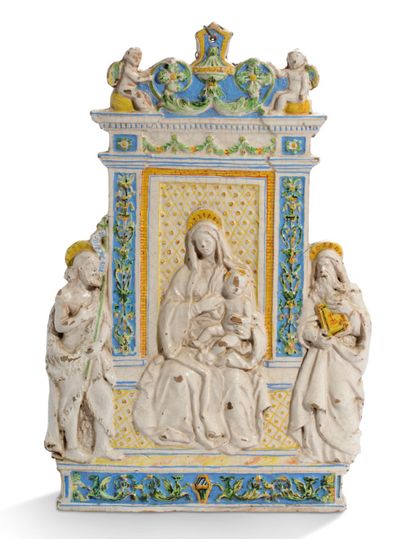 一张白色的陶器虔诚桌，上面有蓝色、绿色和黄色的多色装饰：圣母和孩子坐在壁柱的建筑装饰中。在顶部有一个叶子的花坛，两个天使面对面。在圣母的两边分别站着：施洗者圣约翰和一个传教士。背面釉下铭文：Monastero...
