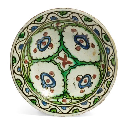 null [IZNIK]
小型硅质陶瓷 "tabak "盘，白底多色装饰，四个蓝色石榴点缀着红色，有绿色边框的储备。底部的岩石和风格化的云朵交替出现。
背面有一个挂孔。
伊兹尼克，17世纪。
直径...