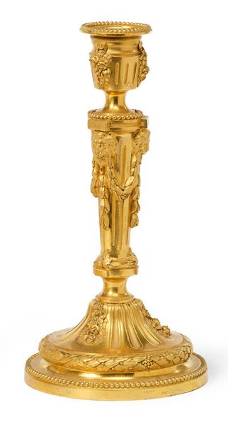 ATTRIBUÉ À PIERRE-PHILIPPE THOMIRE (1751 - 1843) 一对罕见的带凹槽和鎏金的青铜火把。圆形底座上装饰着一排珍珠，一个峡谷和一个月桂树叶和丝带蝴蝶结的花环。上面的斗拱部分呈现出三组下降的笛子，与悬挂的和悬空的玫瑰花束交替出现，并在一个狭窄的地方结束，上面有一个阶梯式的夹板，轴心就放在那里。纺锤形的轴心，其周长分为三个类似的区间，每个区间都呈现出一个狮子的面具，嘴里叼着月桂树叶的花环，与三根笛子交替出现，其上部的尽头是一个带有凸起的夹板，一排珍珠支撑着有脚花瓶形式的插座，让人联想到下部斗拱形式的装饰：悬挂的玫瑰花束和三根垂直笛子的组合。壶嘴的翅膀上有一排珍珠，让人联想到底座。路易十六时期。
高：29厘米...