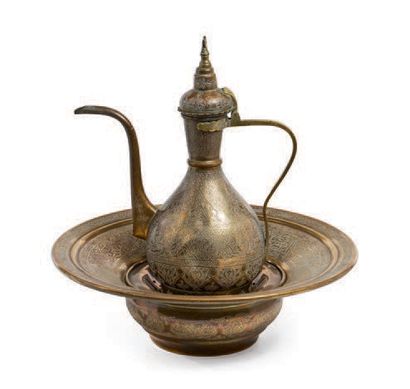 null 一个铜制陶器及其盆子和肥皂盘，上面有丰富的雕刻书信装饰。壶的顶部有一个新月。伊朗，Qadjar，19世纪。
壶身高度：33厘米
盆子的直径：39.5厘...