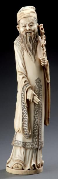 JAPON Sculpture en ivoire représentant un sage, un baton dans une main, un rouleau...