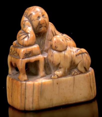 JAPON Netsuké en ivoire sculpté représentant un philosophe appuyé sur une table avec...