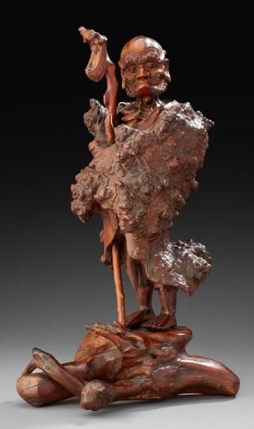 JAPON Racine sculptée représentant un ascete débout sur un tertre enmitoufflé dans...