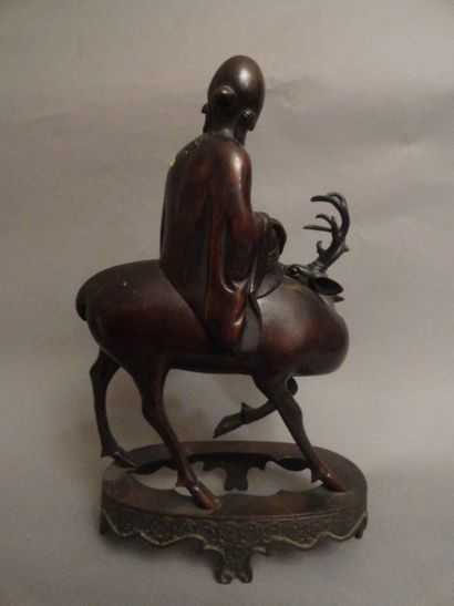 CHINE Figurine en bronze à patine brune figurant Shoulao chevauchant un daim reposant...