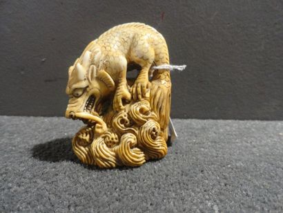 JAPON Netsuke en ivoire sculpté représentant un dragon sur un rocher avec vaguelettes....