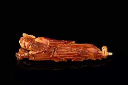 CHINE Figurine en ivoire sculptée à patine brune représentant un Immortel tenant...