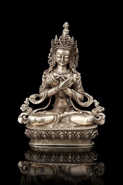TIBET Bouddha en argent en position du lotus sur un socle lotiforme tenant dans ses...