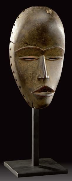 TRAVAIL AFRICAIN Masque en bois sculpté à patine brune. H: 26 cm (léger enfoncement)...