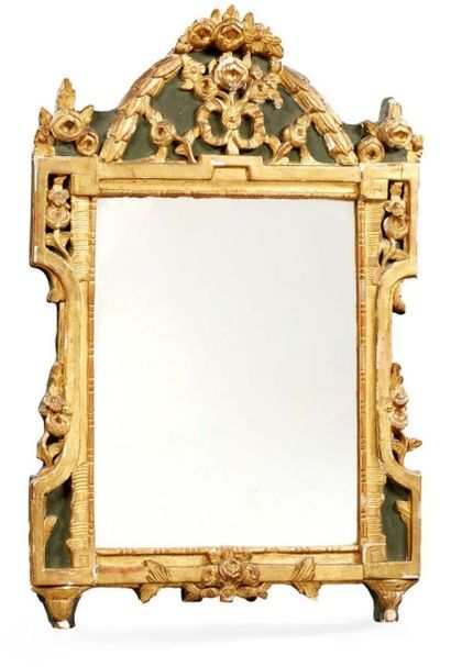 null Miroir dans un cadre en bois sculpté et doré à fronton orné de fleurs stylisées...