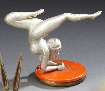 H. RAYMOND, d'après Mascotte en aluminium figurant une jeune femme contorsionniste....