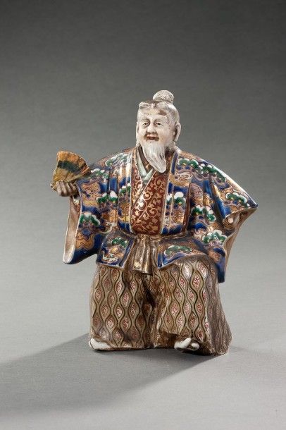 JAPON Figurine en porcelaine représentant un homme portant un riche kimono et brandissant...