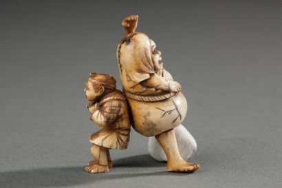 JAPON Netsuke en ivoire constitué de 2 pièces; paysan transportant un personnage...