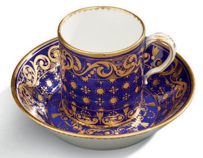 SÈVRES 
Tasse et sous-tasse en porcelaine à fond gros bleu et décor en or appliqué...