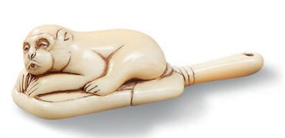 JAPON Netsuke en ivoire représentant un singe couché sur un uchiwa, à moitié assoupi,...